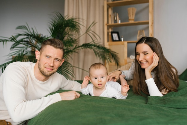 Mutter und Vater liegen mit ihrem kleinen Sohn zu Hause auf dem Bett