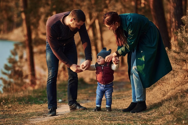 Mutter und Vater mit ihrem kleinen Sohn gehen tagsüber im Frühlingswald spazieren