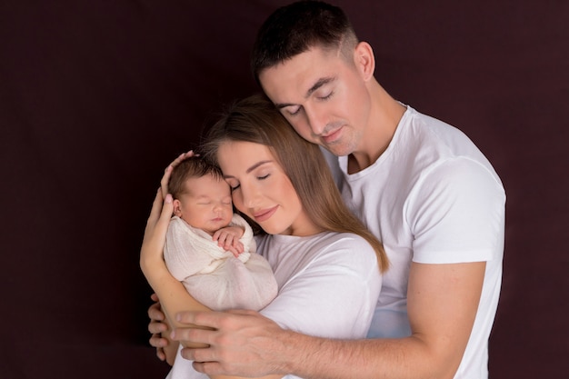 Mutter und Vater umarmen ihr süßes Neugeborenes