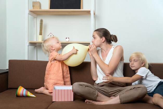 Mutter und zwei Kinder bereiten sich auf den Urlaub vor. Mama bläst den Ballon auf. Glückliche Kindheit