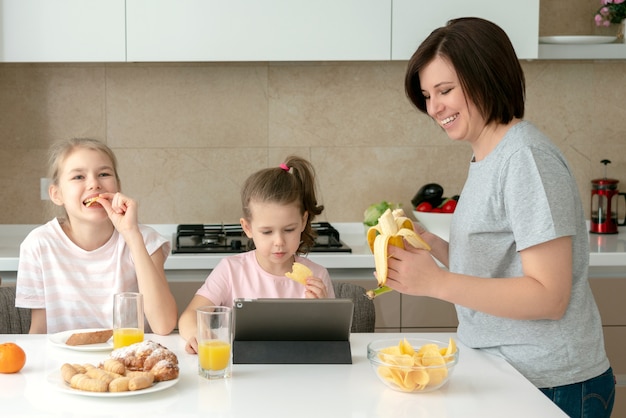 Mutter und zwei Töchter, die zusammen frühstücken, glückliches alleinerziehendes Familienkonzept