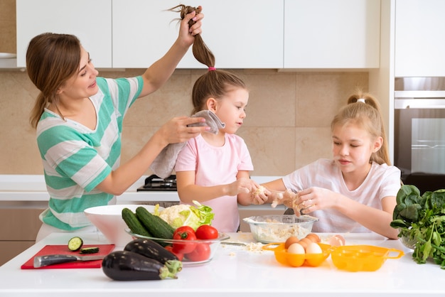 Mutter und zwei Töchter kochen in der Küche und haben Spaß, glückliche Familie und alleinerziehende Mutter Konzept