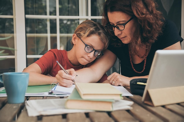 Mutter unterrichtet ihren Sohn, während sie zu Hause am Tisch sitzt