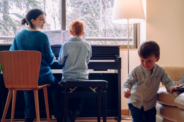 Mutter unterrichtet ihren Sohn zu Hause Klavierunterricht. Familienlebensstil, der Zeit zusammen drinnen verbringt. Kinder mit musikalischer Tugend und künstlerischer Neugier.