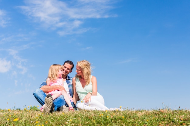 Mutter, Vater, Kind sitzen im Freien