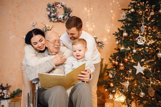 Mutter, Vater, kleiner Sohn und alter Großvater im Rollstuhl, der neben dem Weihnachtsbaum sitzt