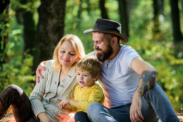 Mutter, Vater und kleiner Sohn sitzen Waldpicknick Guten Tag für Frühlingspicknick in der Natur Erkunden Sie die Natur zusammen Familientag-Konzept Mutter, Vater und Kind, Junge, entspannen beim Wandern im Wald Familienpicknick