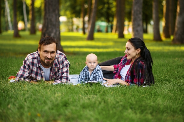 Mutter, Vater und kleines Baby entspannen auf Gras im Sommerpark