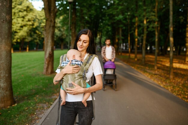 Mutter, Vater und kleines Baby gehen entlang der Gasse im Sommerpark