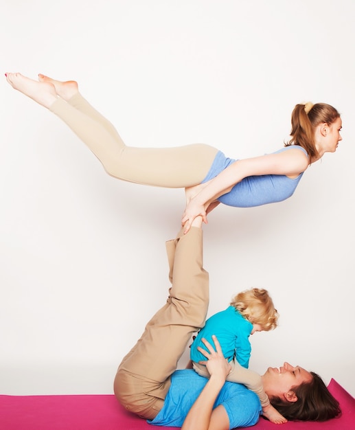 Mutter, Vater und Sohn beim Yoga auf weißem Hintergrund