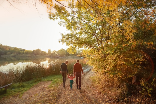 Mutter, Vater und Tochter gehen auf den Waldweg Dreier und gehen direkt zum Waldsee