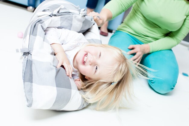 Foto mutter wiegt ihre tochter mit dem kissen auf dem boden