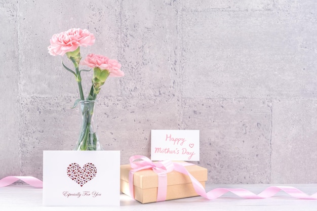 Muttertag handgefertigte Geschenkkiste Überraschung Wünsche Fotografie Schöne blühende Nelken mit rosa Band Kiste isoliert auf grauer Tapete Design Close-up Kopie Raum Mock-up