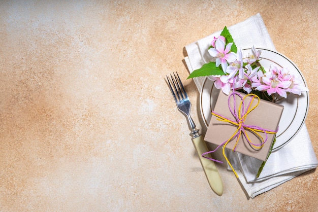 Muttertag Hochzeit Geburtstag Frühlingsferien Grußkarte Hintergrund Muttertag Tischdekoration Flatlay mit Teller Gabel Messer Frühlingsblumen Geschenkbox vorhanden mit Band Draufsicht Kopierraum