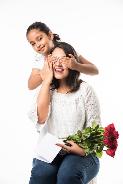 Muttertag - Indisches Mädchen und Mutter feiern den Muttertag mit Rosenblumenstrauß, Grußkarte beim Umarmen und Küssen