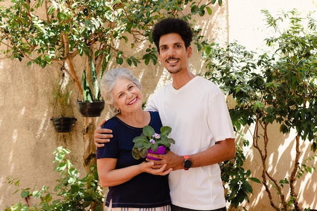 Muttertag Kaukasische Mutter erhält Blumen von ihrem schwarzen Sohn im Garten zu Hause