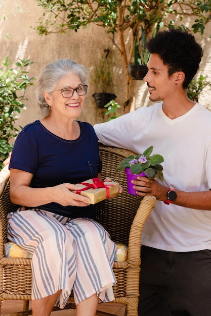 Muttertag Kaukasische Mutter und ihr schwarzer Sohn mit Geschenk im Hausgarten Happy interracial family