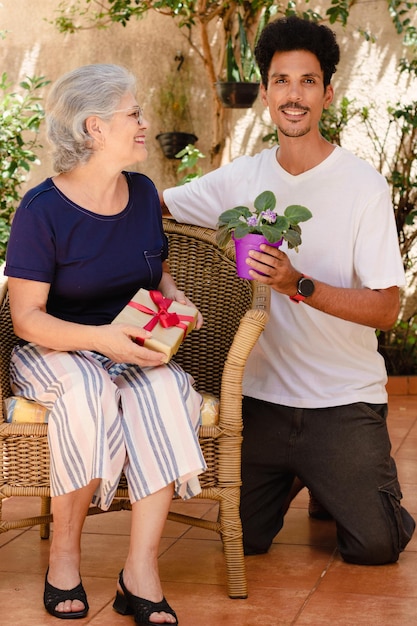 Muttertag Kaukasische Mutter und ihr schwarzer Sohn mit Geschenk im Hausgarten Happy interracial family