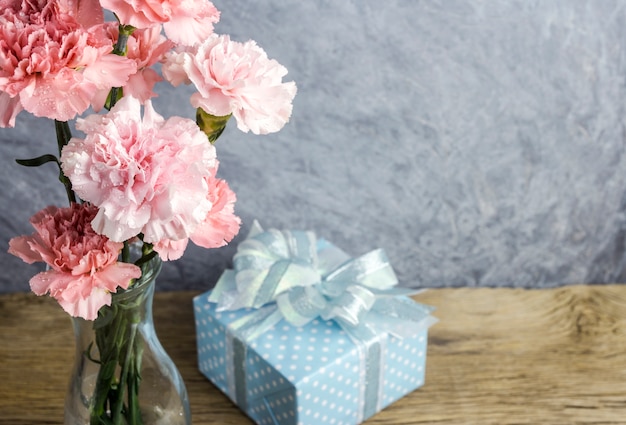 Muttertagkonzept der rosa Gartennelke blüht in der klaren Flasche und in der Geschenkbox