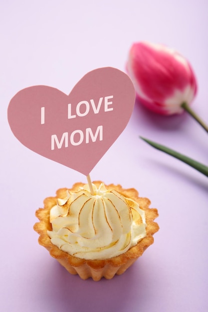Muttertagsnachricht mit Cupcake und Tulpe auf violettem Hintergrund Vertikales Foto