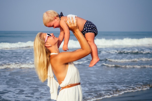 Muttertochter, die Spaß hat, sich am Strand auszuruhen. Familienurlaub reisen. Kaukasische Frau mit Kleinkindbaby am Ozean.