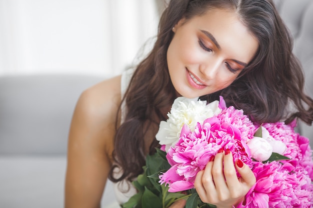 Muy bella mujer con flores y regalos en el interior