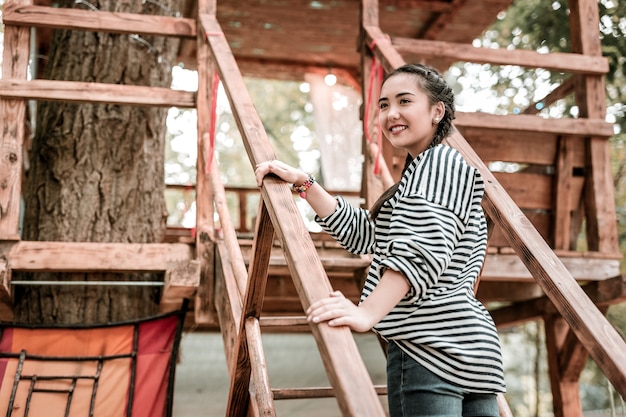 Muy contento. Encantadora mujer joven manteniendo una sonrisa en su rostro mientras mira a un lado