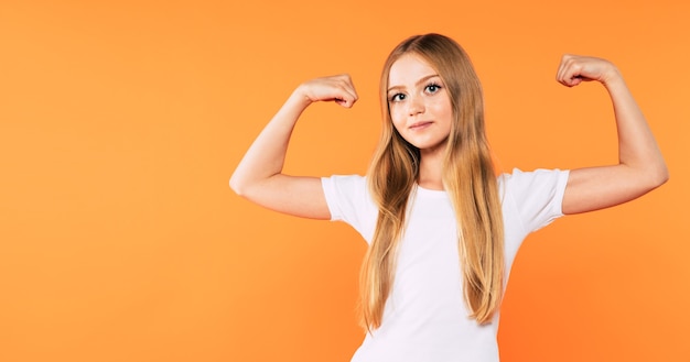 Muy emocionada y feliz hermosa niña rubia en camiseta blanca tiene una diversión y posando y gritando aislado sobre fondo amarillo