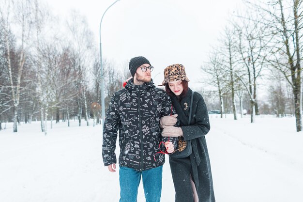 Muy joven moda hermosa pareja de amantes en ropa elegante con chaqueta camina juntos al aire libre en un día de invierno nevado