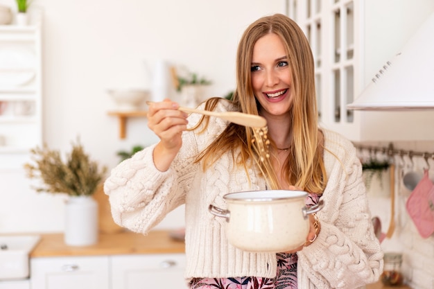 Muy linda mujer rubia preparando comida en rosa acogedor