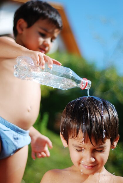 Muy lindo niño jugando con agua al aire libre