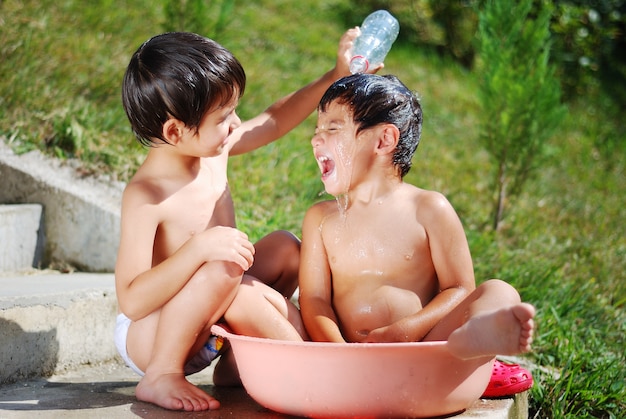 Muy lindo niño jugando con agua al aire libre