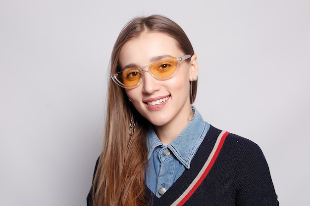 Muy sonriente alegremente mujer con cabello rubio, vestida de manera informal, mirando con satisfacción a la cámara, siendo feliz. Disparo de estudio de mujer hermosa guapa aislada contra la pared del estudio en blanco