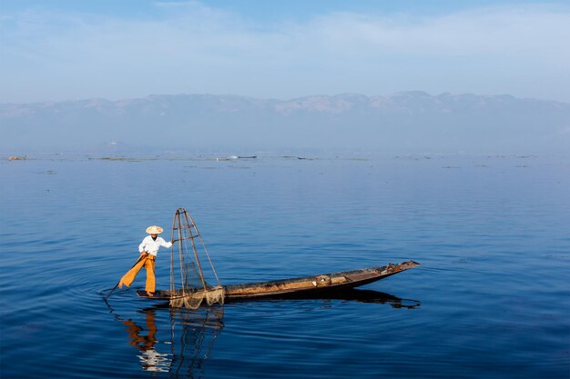 Myanmar Reiseattraktion Wahrzeichen Traditioneller burmesischer Fischer balanciert mit Fischernetz am Inle-See Myanmar ist berühmt für seinen unverwechselbaren einbeinigen Ruderstil