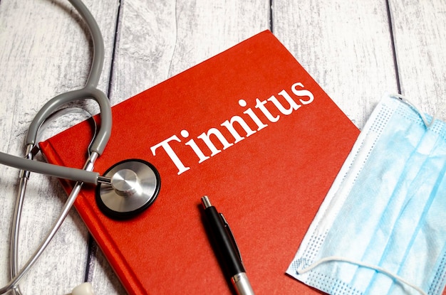 N o texto do caderno TINNITUS na mesa ao lado do estetoscópio