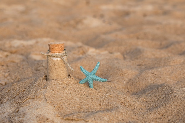 Na areia em uma garrafa de areia do mar e uma estrela do mar perto