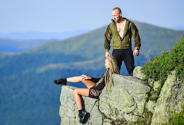 Na beira do mundo Mulher sentada à beira do penhasco fundo de paisagem de montanhas altas Casal de caminhantes aprecia a vista Caminhada momento de paz Turista alpinista menina e homem relaxante Caminhadas benefícios Fim de semana de caminhada