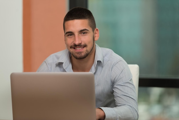 Na biblioteca Bonito estudante do sexo masculino com laptop e livros trabalhando em uma biblioteca da universidade do ensino médio Profundidade de campo rasa