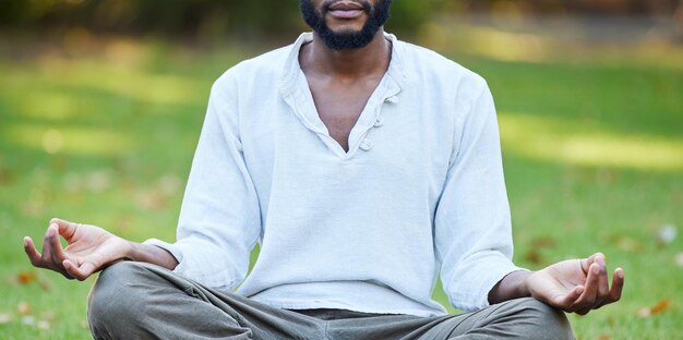 Na busca pela paz interior Foto recortada de um jovem irreconhecível meditando enquanto pratica ioga lá fora no parque