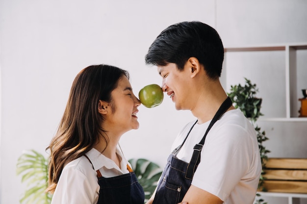 Na cozinha Casal perfeitamente feliz Preparando comida saudável Muitos vegetais Homem Faz malabarismo com frutas Faz a namorada rir Pessoas adoráveis se divertem