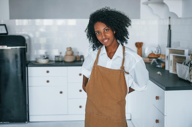 Na cozinha Jovem afro-americana com cabelo encaracolado dentro de casa em casa