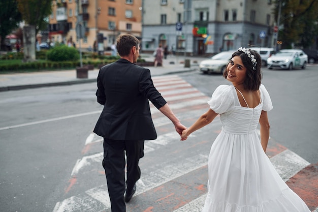 Na faixa de pedestres A noiva bonita com seu noivo está comemorando o casamento ao ar livre