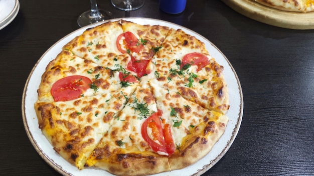 Na foto, pizza de queijo com tomate servido em um prato.