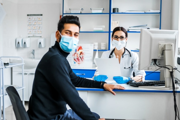 Na foto, um médico e um paciente, um médico sentado à mesa, o consultam e olham para o khmer com um sorriso