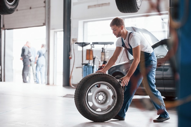 Na garagem. Empregada com uniforme azul trabalha no salão automóvel.