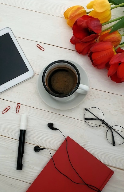 Na mesa do escritório de uma mulher de negócios, há uma xícara de café preto e um laptop de papelaria