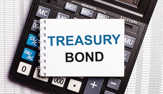 Na mesa estão os relatórios, uma calculadora e um cartão com as palavras treasury bond.