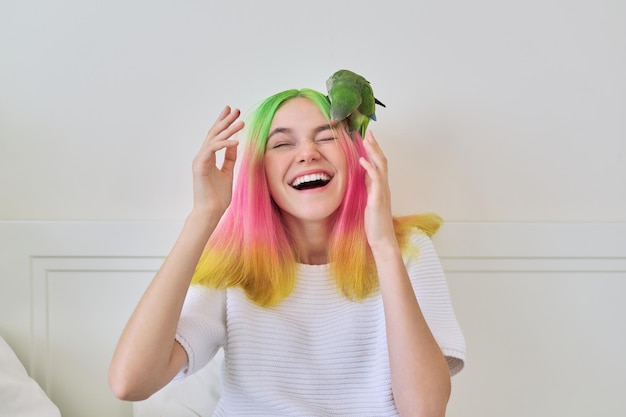 Na moda na moda com adolescente penteado de cores vivas com quaker verde jovem papagaio na cabeça amizade de adolescente e estilo de vida de pássaro de adolescente e animal de estimação