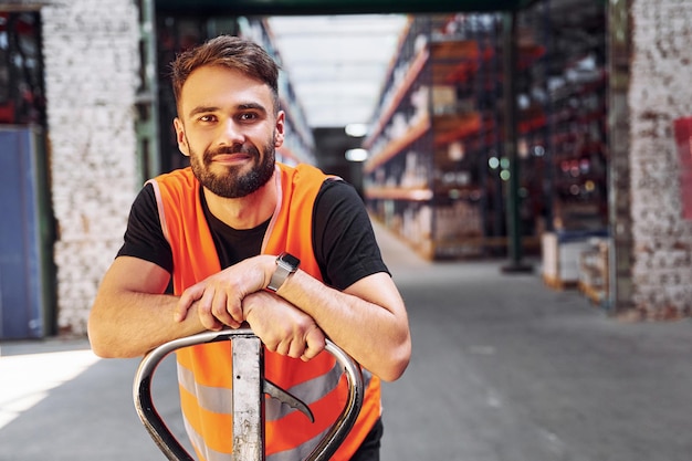 Na plataforma do carrinho, o trabalhador de armazenamento está no armazém com um monte de produtos