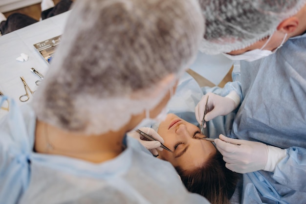 Na sala de cirurgia do hospital equipe diversificada de cirurgiões profissionais e enfermeiras sutura de ferida após cirurgia bem-sucedida